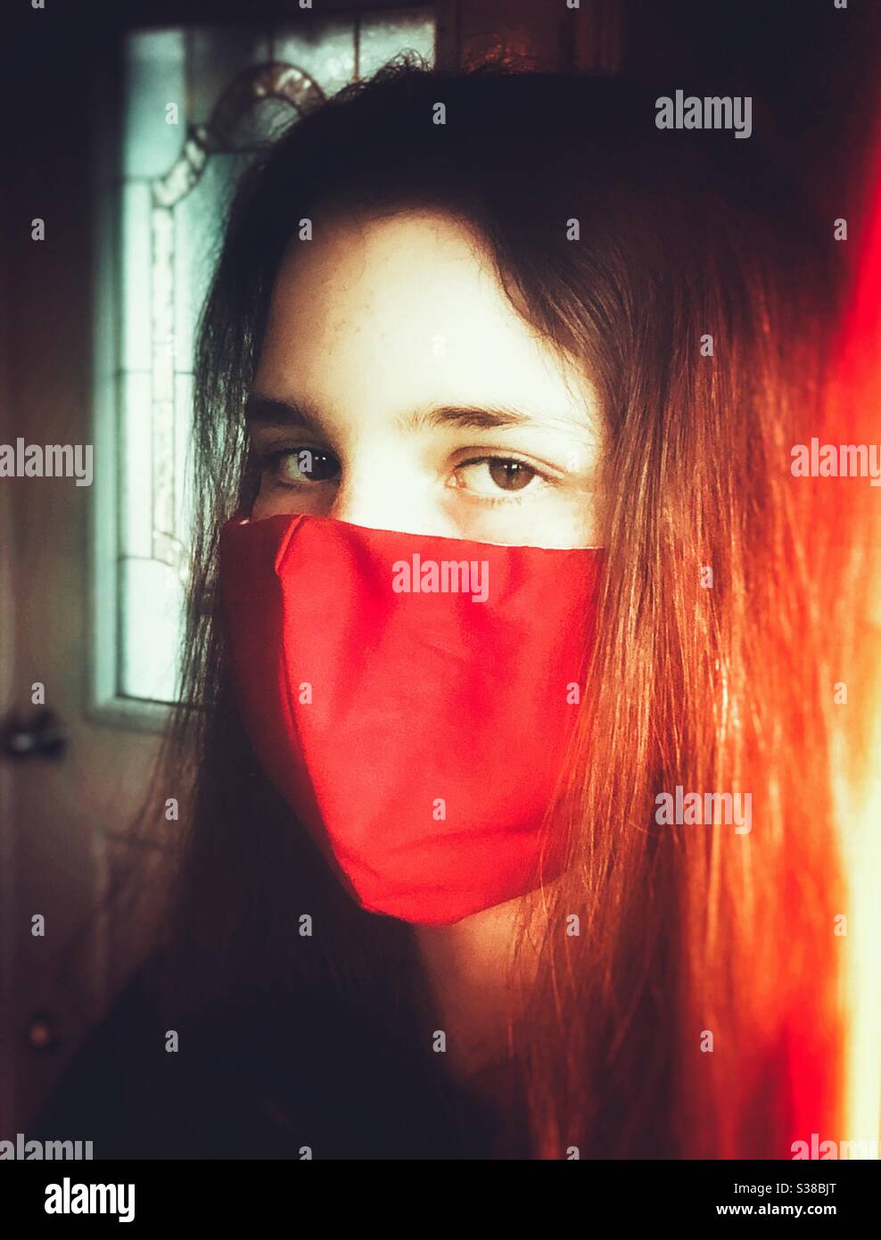 Teen girl wearing red, cotton homemade face mask Stock Photo