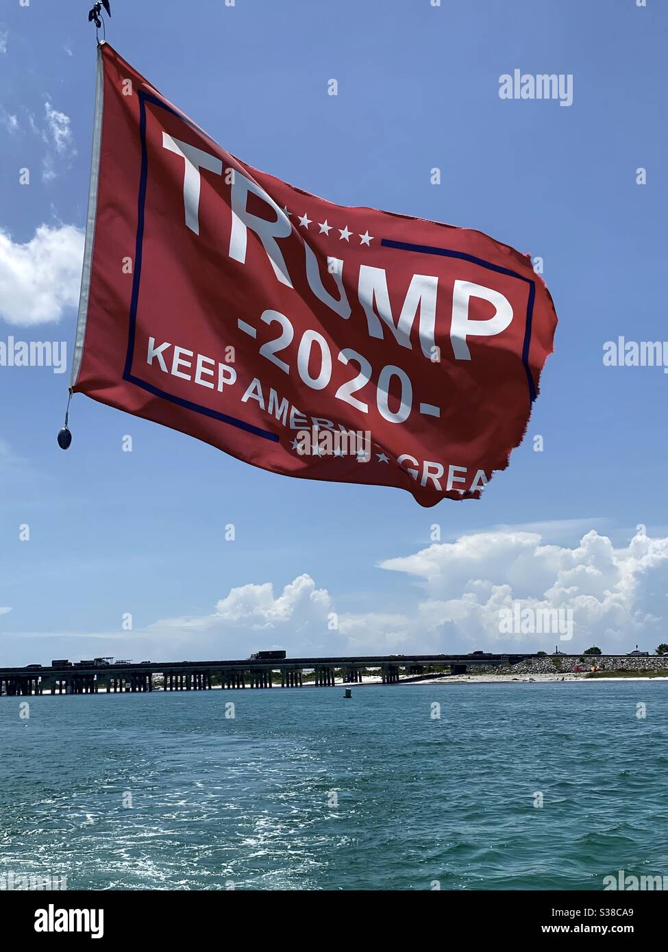 Waving political Trump flag hanging from a boat over water - Smartphone Captured Stock Image