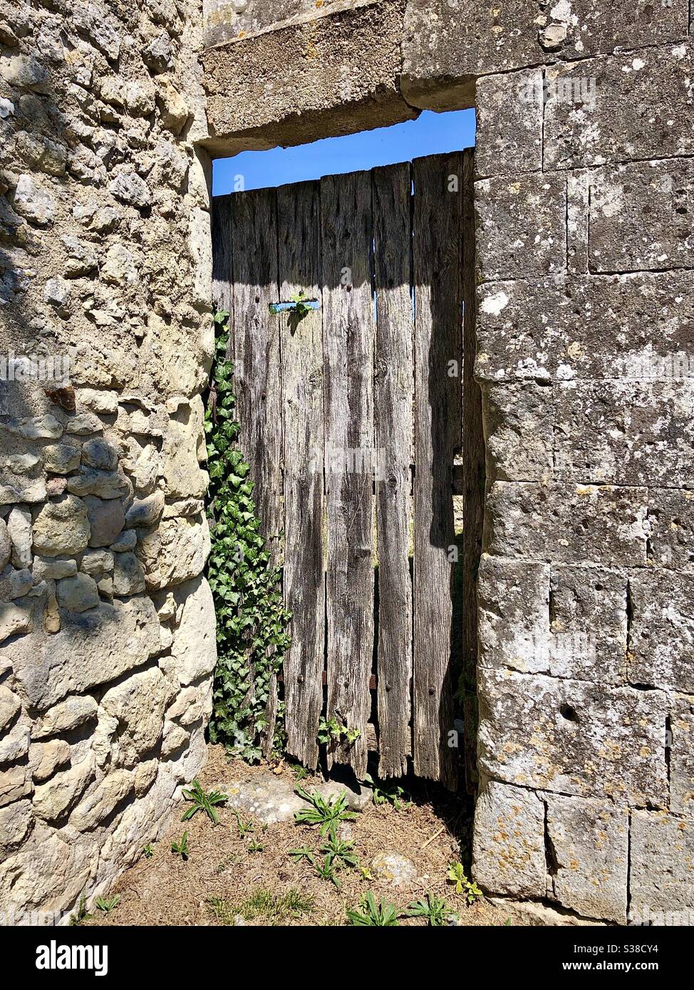 Old wooden doorway in stone wall - France. - Smartphone Captured Stock Image