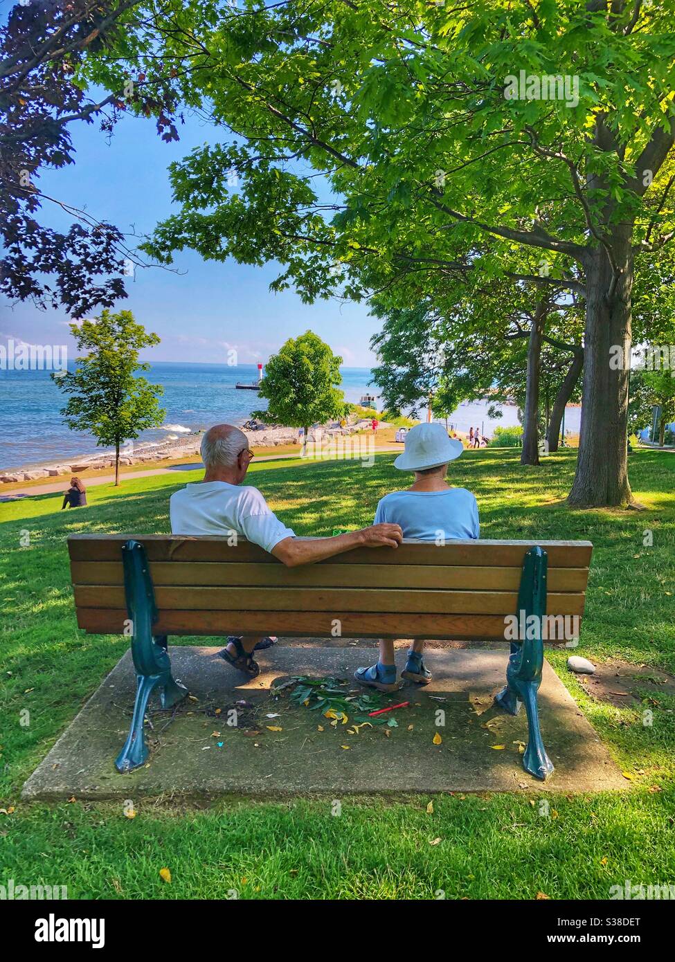 An elderly couple sitting on a bench in the shade. - Smartphone Captured Stock Image