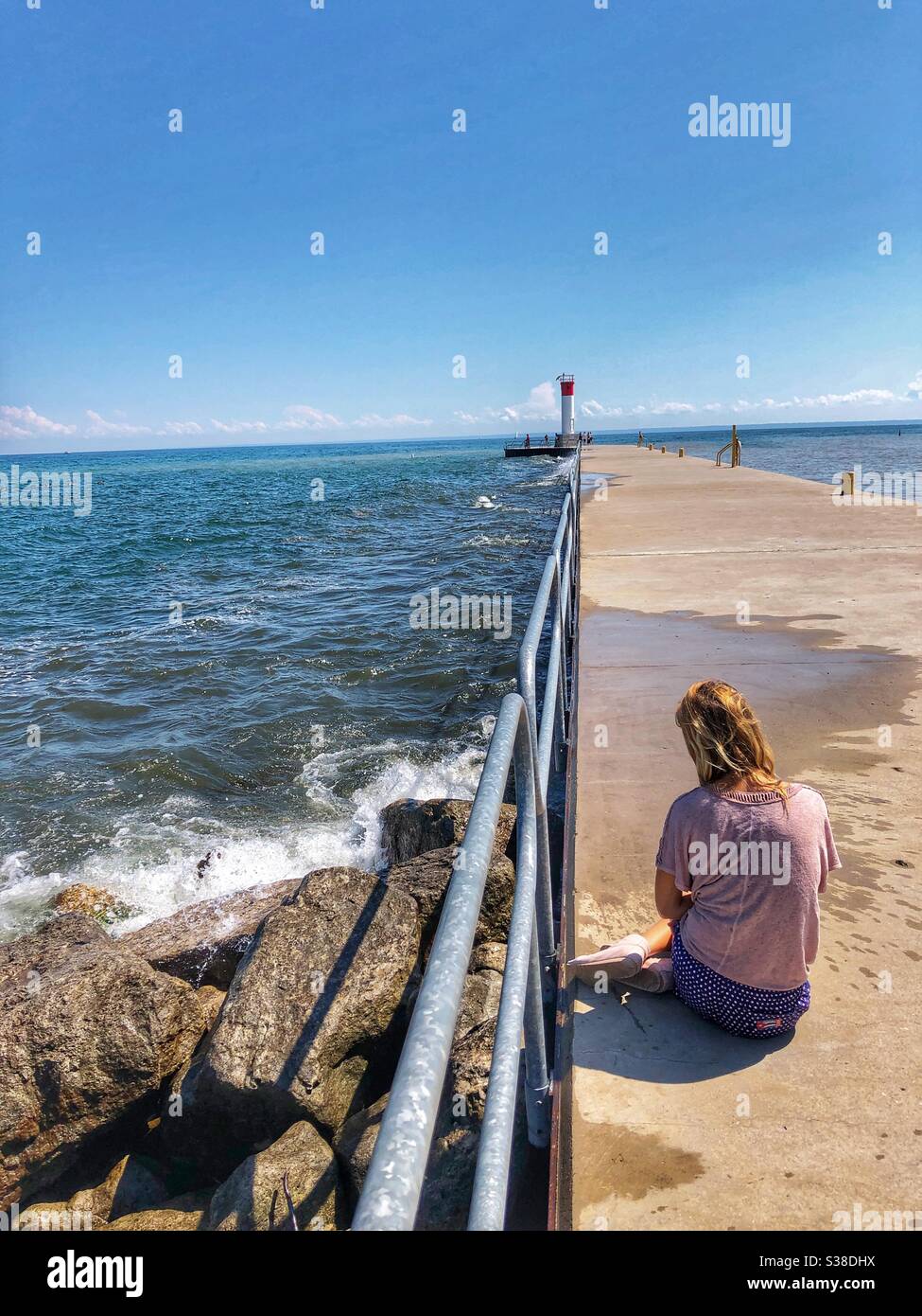 A woman sitting on the pier in Oakville, Ontario, Canada. Stock Photo