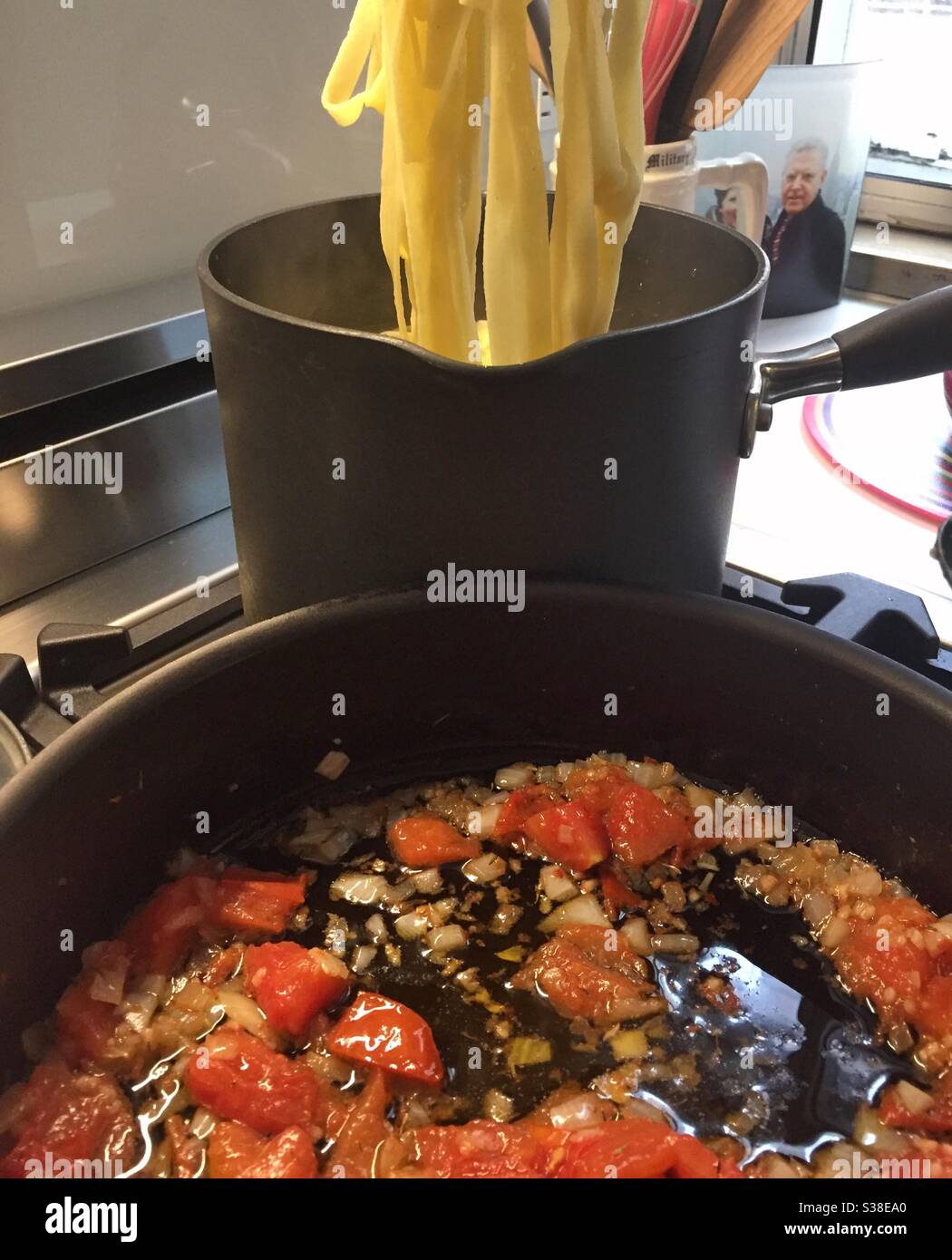 Still life of fettuccine noodles being prepared with a sun-dried tomato sauce on a residential kitchen stove top, USA - Smartphone Captured Stock Image