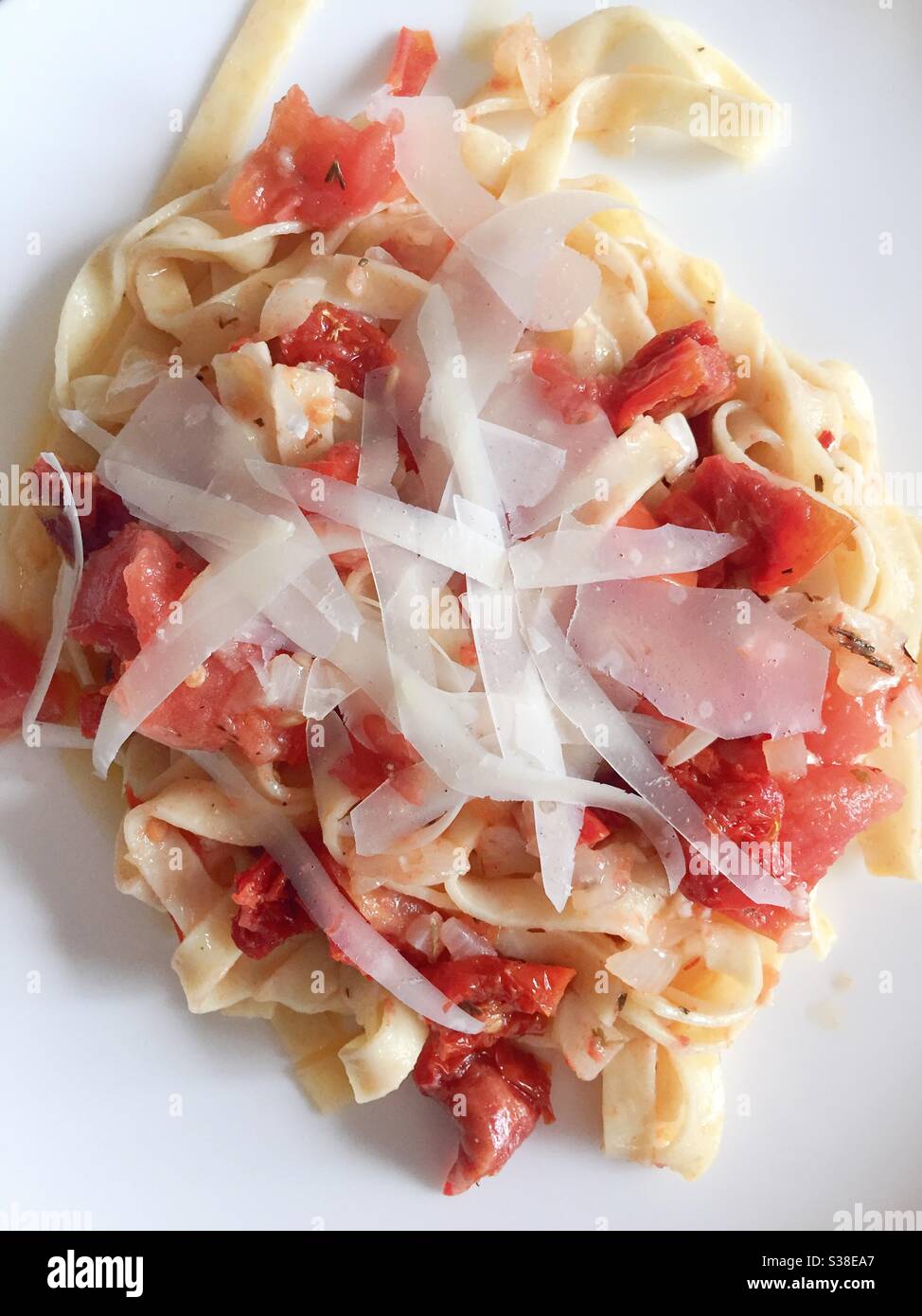 Close up of a fettuccine pasta dish with a sun-dried tomato dressing and shaved Parmesan cheese slivers, USA - Smartphone Captured Stock Image