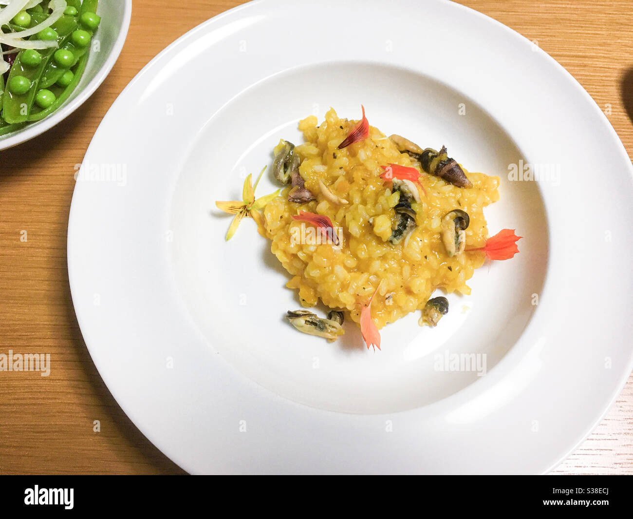 Creamy yellow Seashell risotto with edible flowers and beans salad