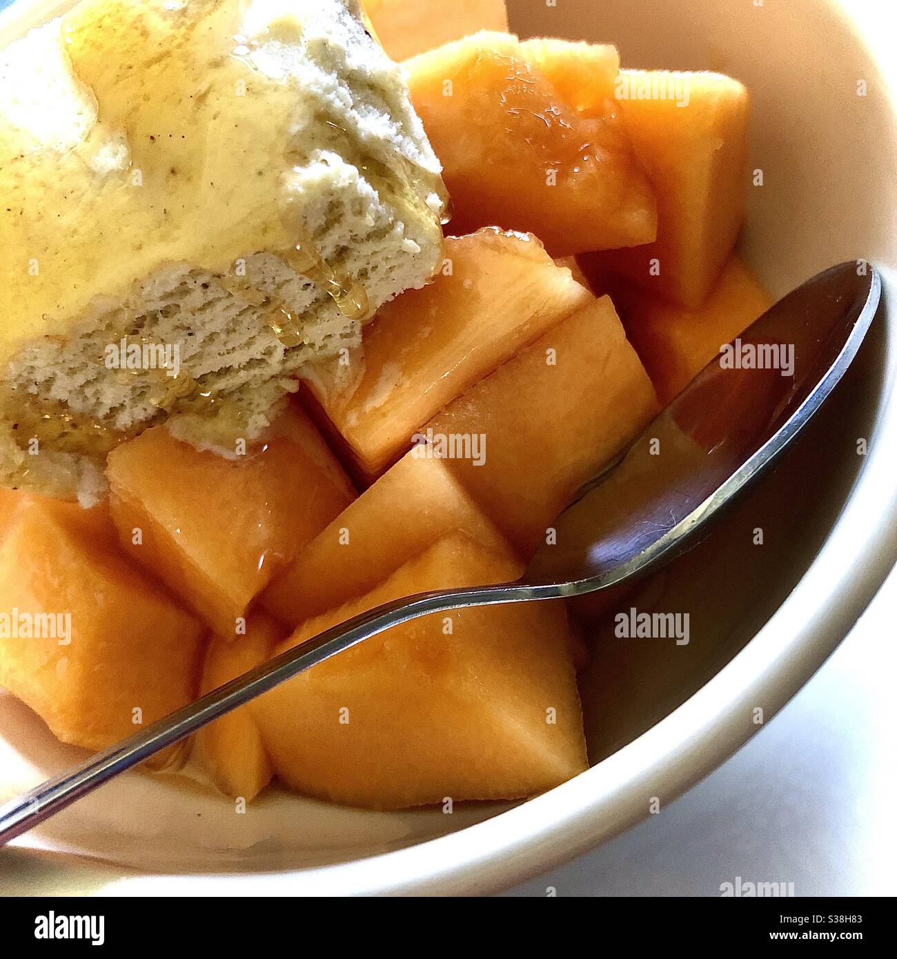 Vanilla ice cream with honey drizzle on melon chunks - all organic. Stock Photo