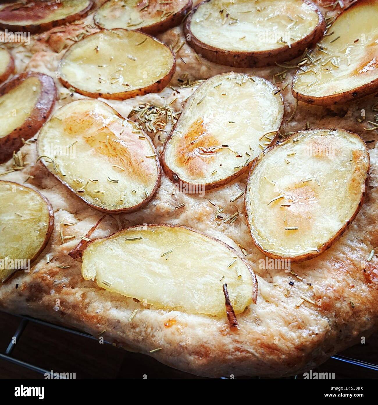 A close up photograph of focaccia bread with potato and rosemary