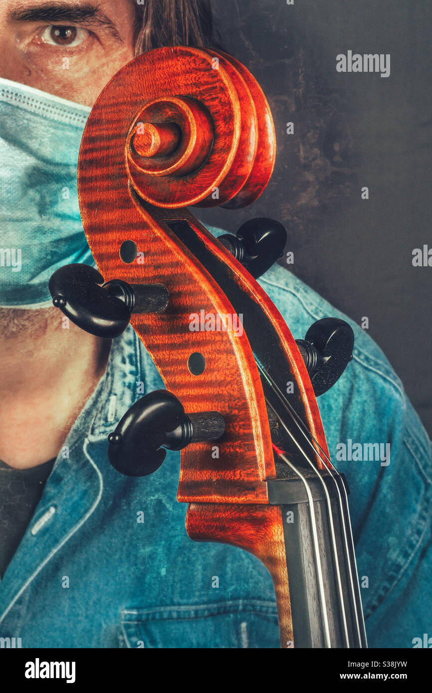 Male white Caucasian musician wearing face mask holding his cello - Smartphone Captured Stock Image