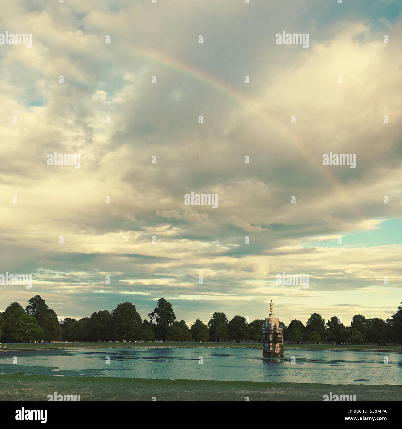 The Diana Fountain in Bushy Park with atmospheric sky and rainbow during a summers evening. Uk - Smartphone Captured Stock Image
