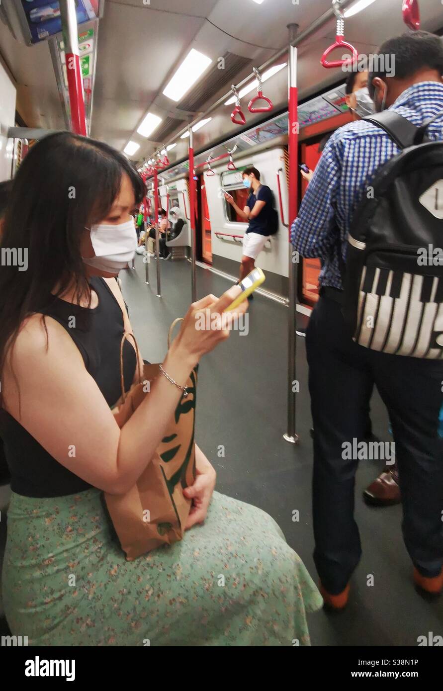 A woman wearing a protective mask using her smartphone. Stock Photo