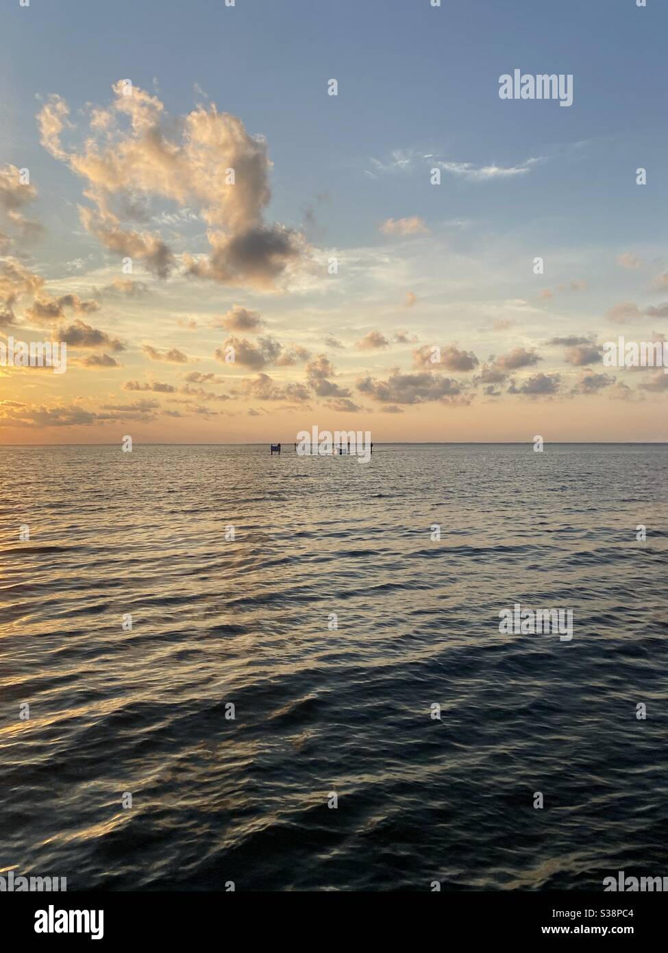 Golden sunset skies over bay water with sea doo boats on the water - Smartphone Captured Stock Image