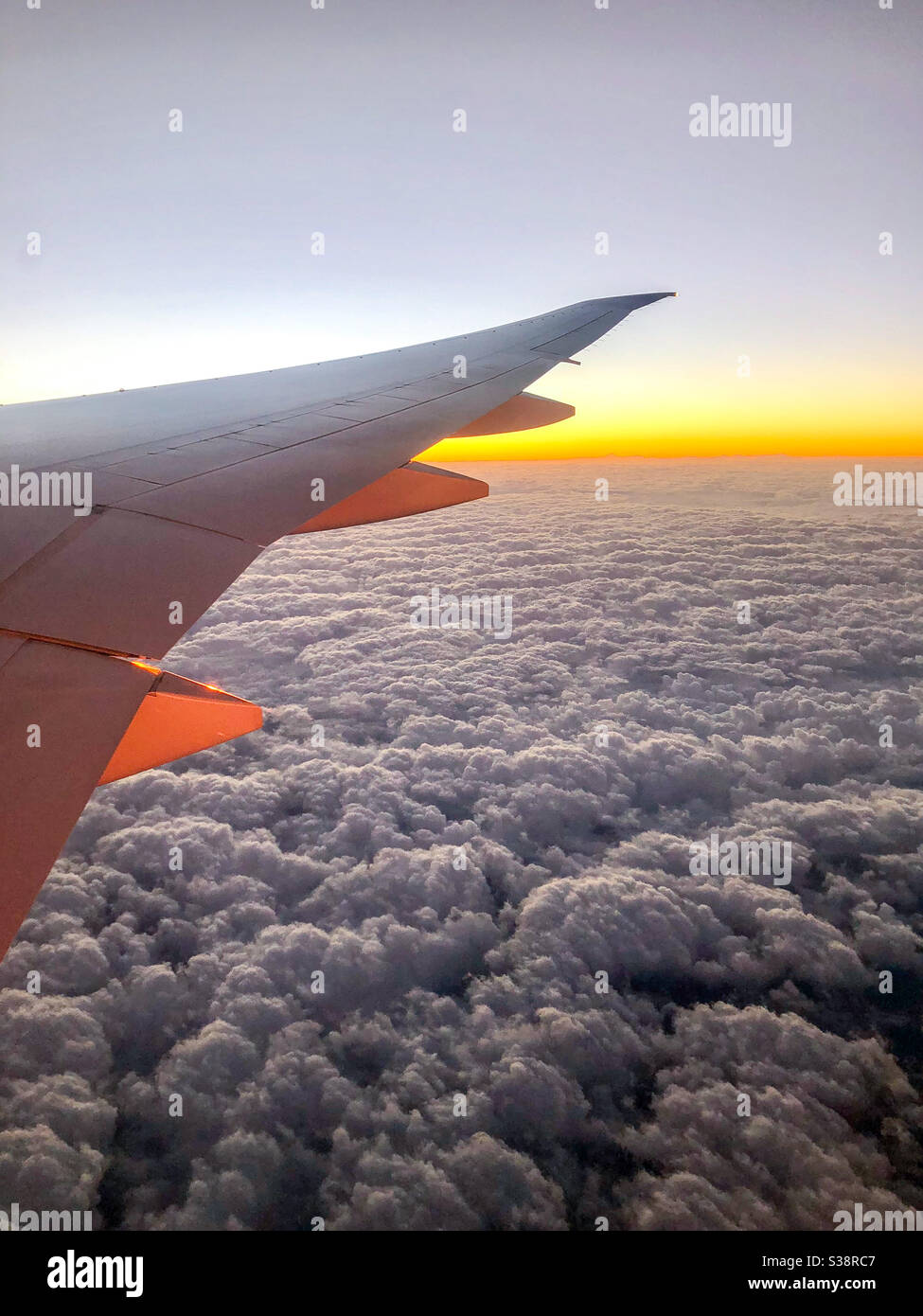 https://c8.alamy.com/comp/S38RC7/window-view-from-a-plane-seat-showing-the-airplane-wing-at-sunrise-with-clouds-S38RC7.jpg