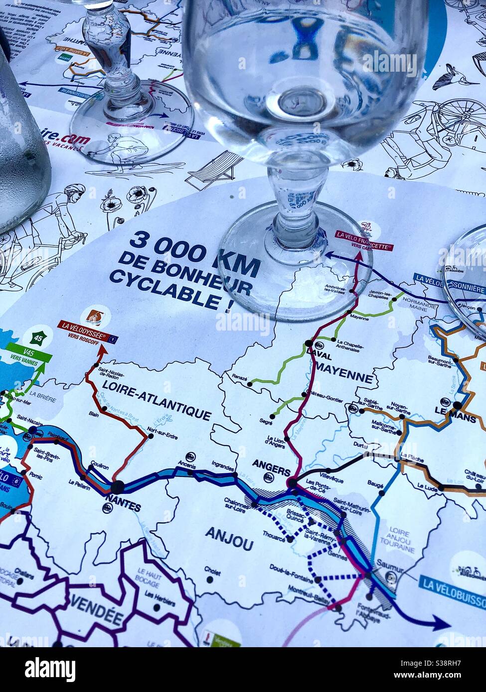 Map of western France showing cycle routes on table with water glasses. - Smartphone Captured Stock Image