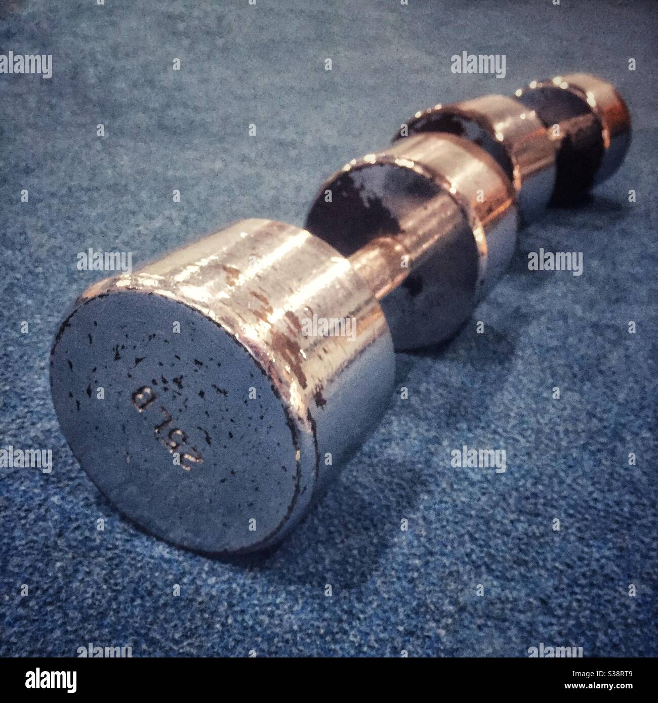A pair of silver colored worn dumbbells on a gym floor. - Smartphone Captured Stock Image