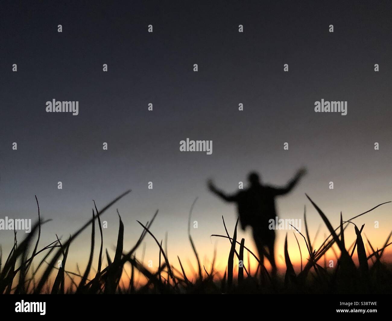 Silhouette of a person weaving her arms at sunset - Smartphone Captured Stock Image