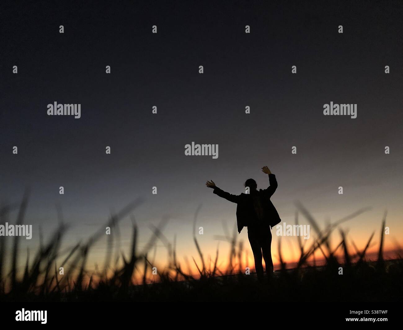 Silhouette of a person weaving her arms at sunset - Smartphone Captured Stock Image