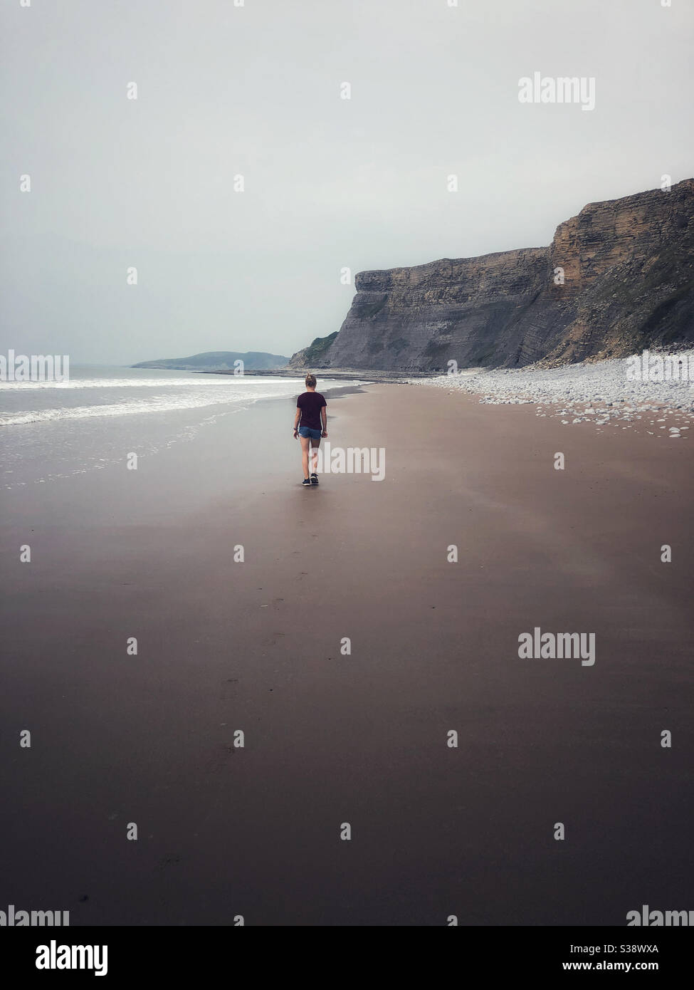 Young girl walking across an deserted beach Stock Photo