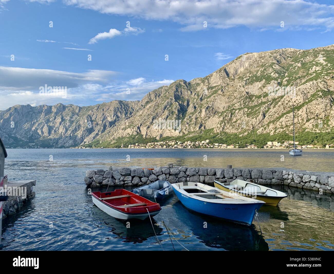 Boats floating on the sea in front of a mountain in Montenegro Stock Photo