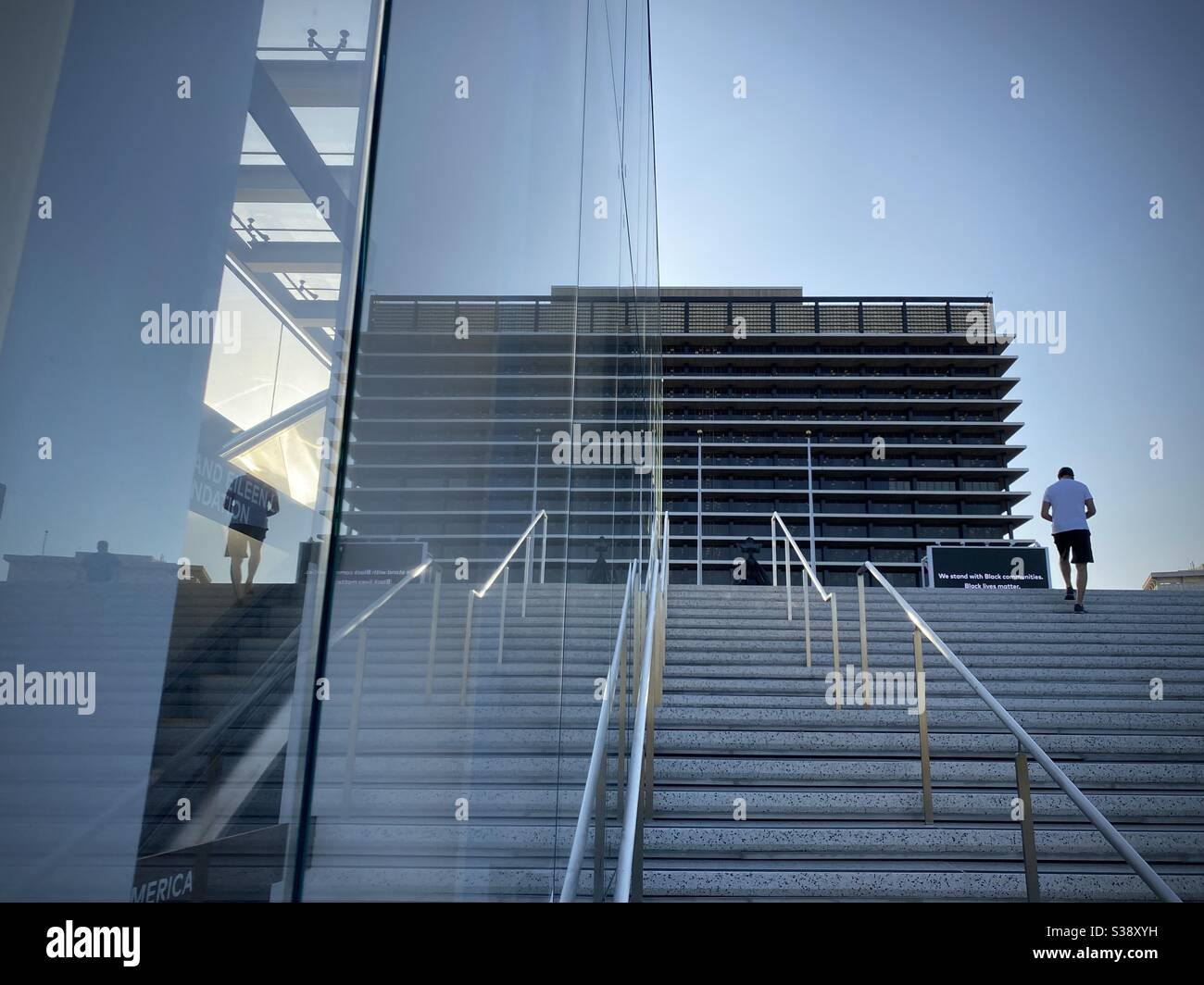 LOS ANGELES, CA, JUN 2020: looking up stairs next to the Music Center in Downtown, with headquarters of the LA Dept of Water and Power reflected in windows. Person stands at top of steps. - Smartphone Captured Stock Image