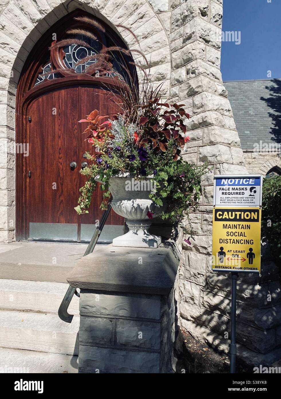 The new normal of church. Signs at the front door reminding worshippers if masks and social distancing requirements. - Smartphone Captured Stock Image