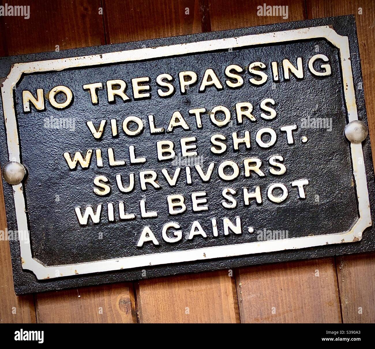 Cast-iron plaque trespass warning notice, with added humour. Stock Photo