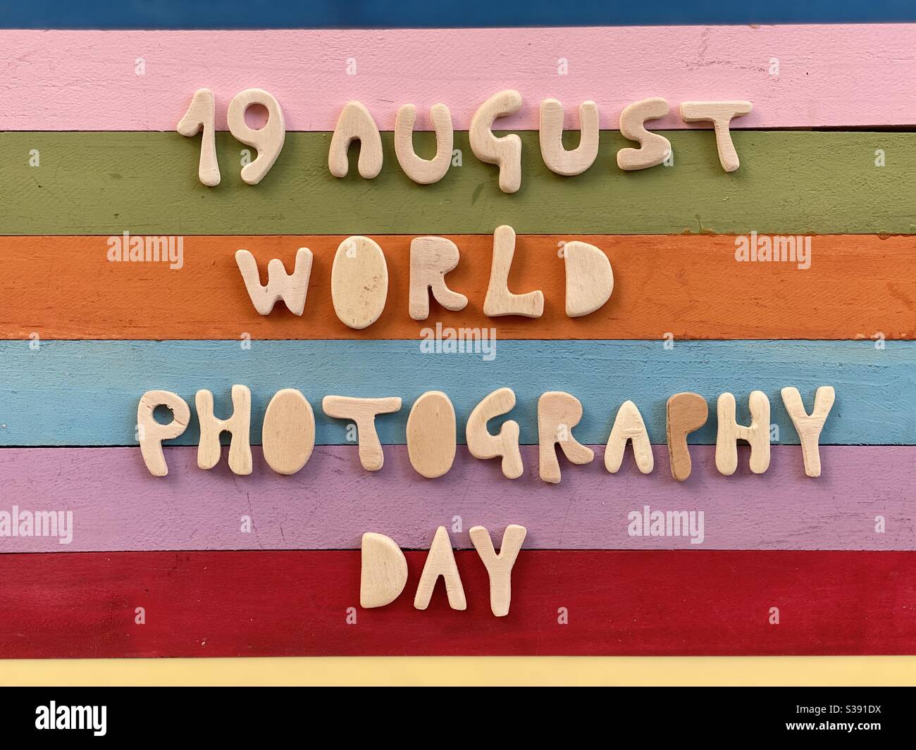 19 August, World Photography Day celebrated with handmade wooden letters over a multicolored wooden board - Smartphone Captured Stock Image
