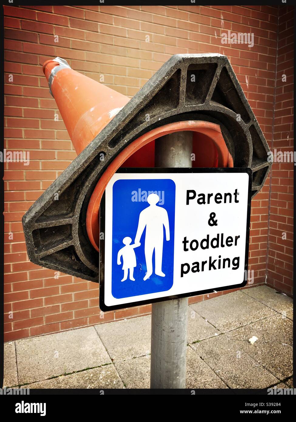 Public information sign about parking for parents with toddlers outside DG One sports centre in Dumfries, Scotland.  A traffic cone has been added. - Smartphone Captured Stock Image