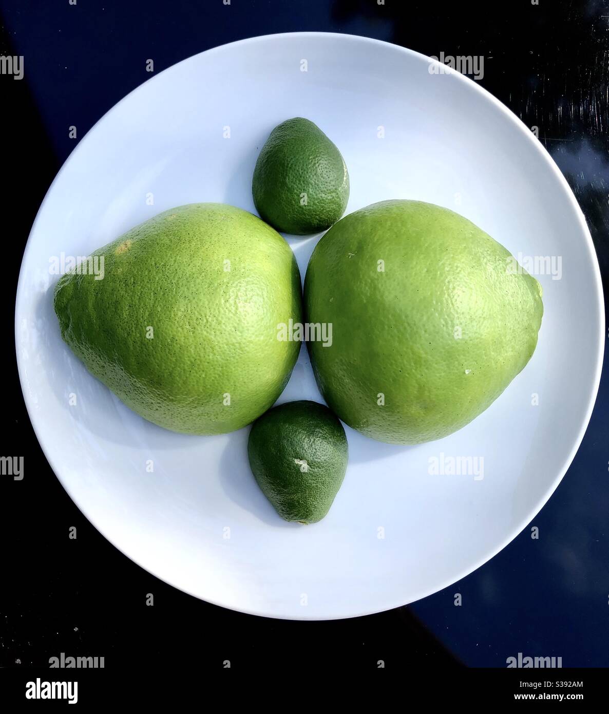 Two different sized pomelo fruits cut in half showing the outside skin. - Smartphone Captured Stock Image