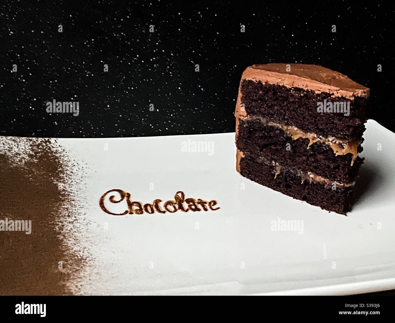 Chocolate caramel layer cake with the word chocolate written in chocolate with a dusting of cocoa powder on left side. - Smartphone Captured Stock Image
