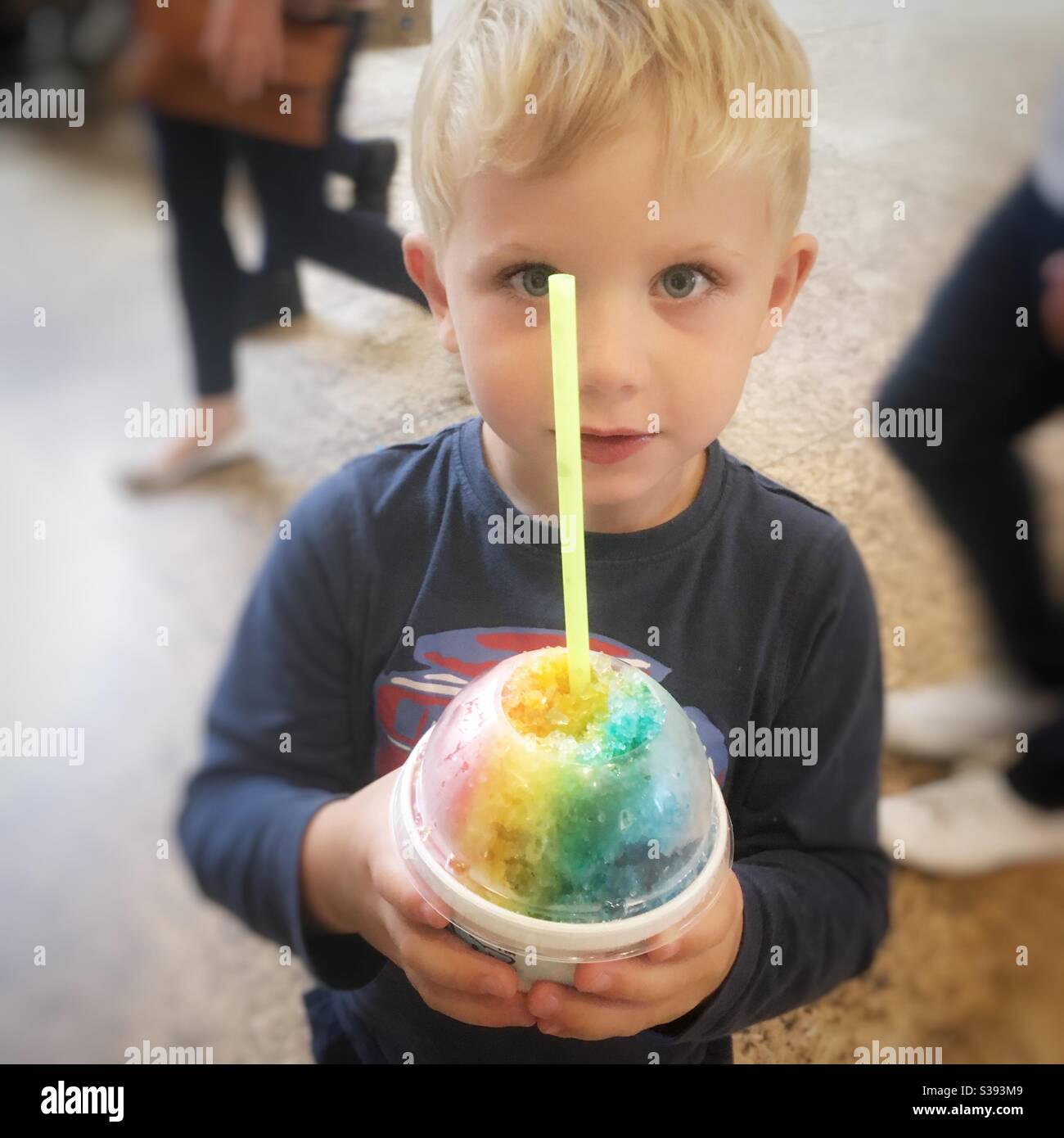 Three year old boy with a rainbow snow cone. Sheffield, England, United Kingdom. Stock Photo
