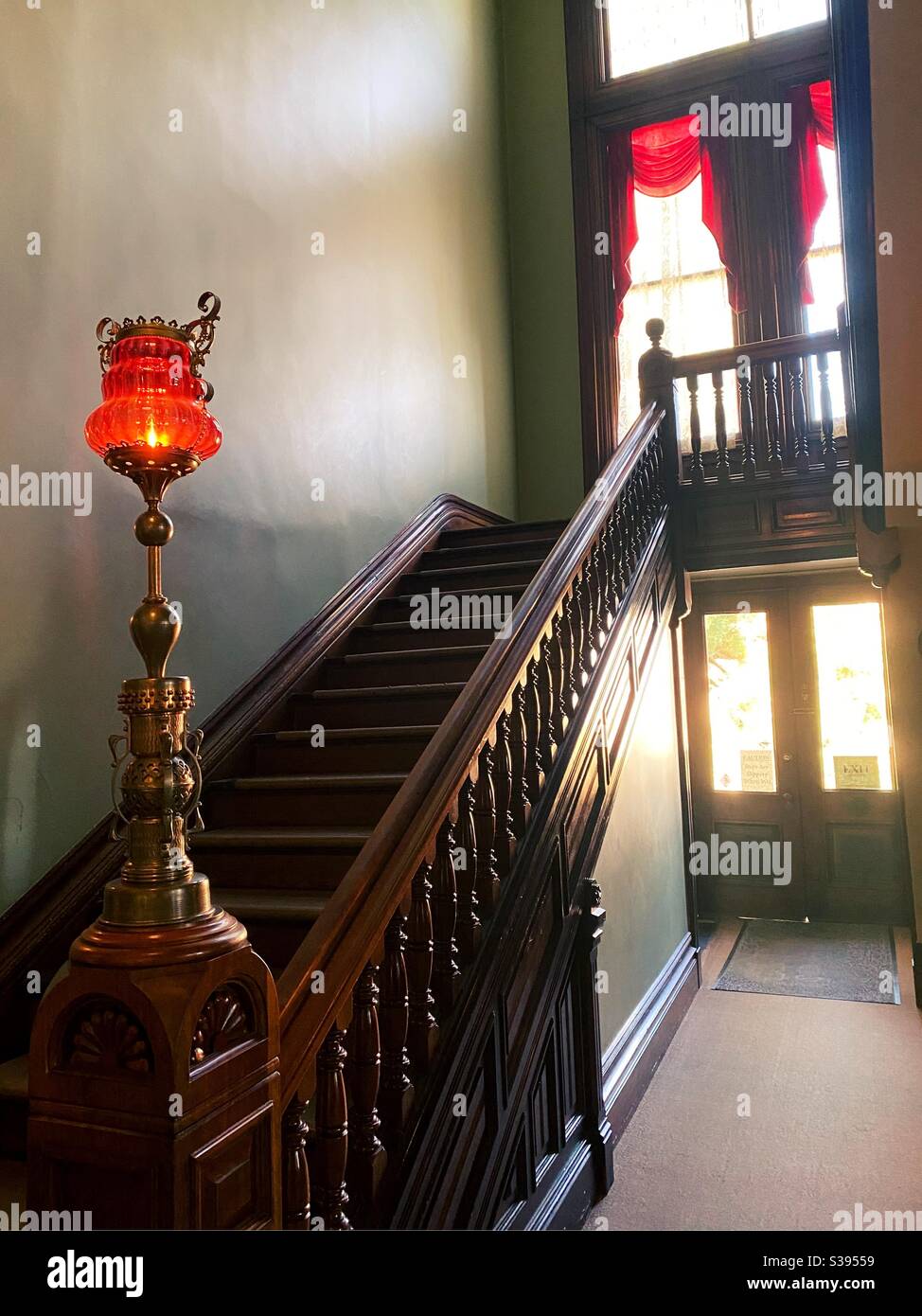 A glass lamp on the newel post of a banister in a Queen Anne style house. Stock Photo