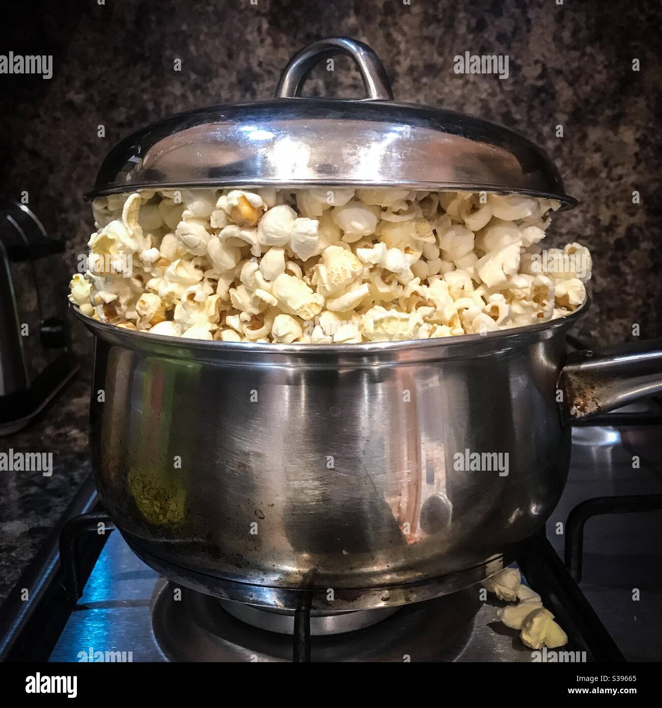 Popcorn overflowing in a pot on a gas hob Stock Photo