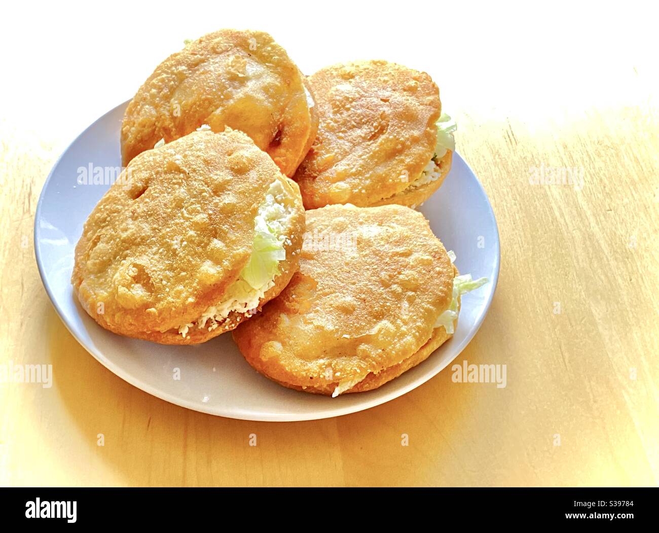 A plate with A close up of a Gordita 'chubby' in Spanish is a Mexican cuisine is a pastry made with maize dough and stuffed with cheese, meat, or other fillings. Stock Photo