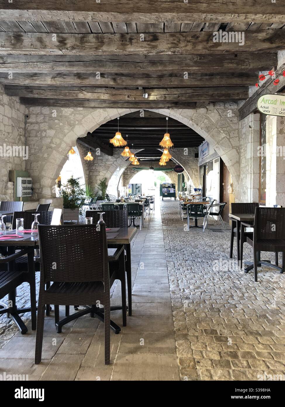 Restaurant tables set up under the arcade in the town of Eymet in France Stock Photo