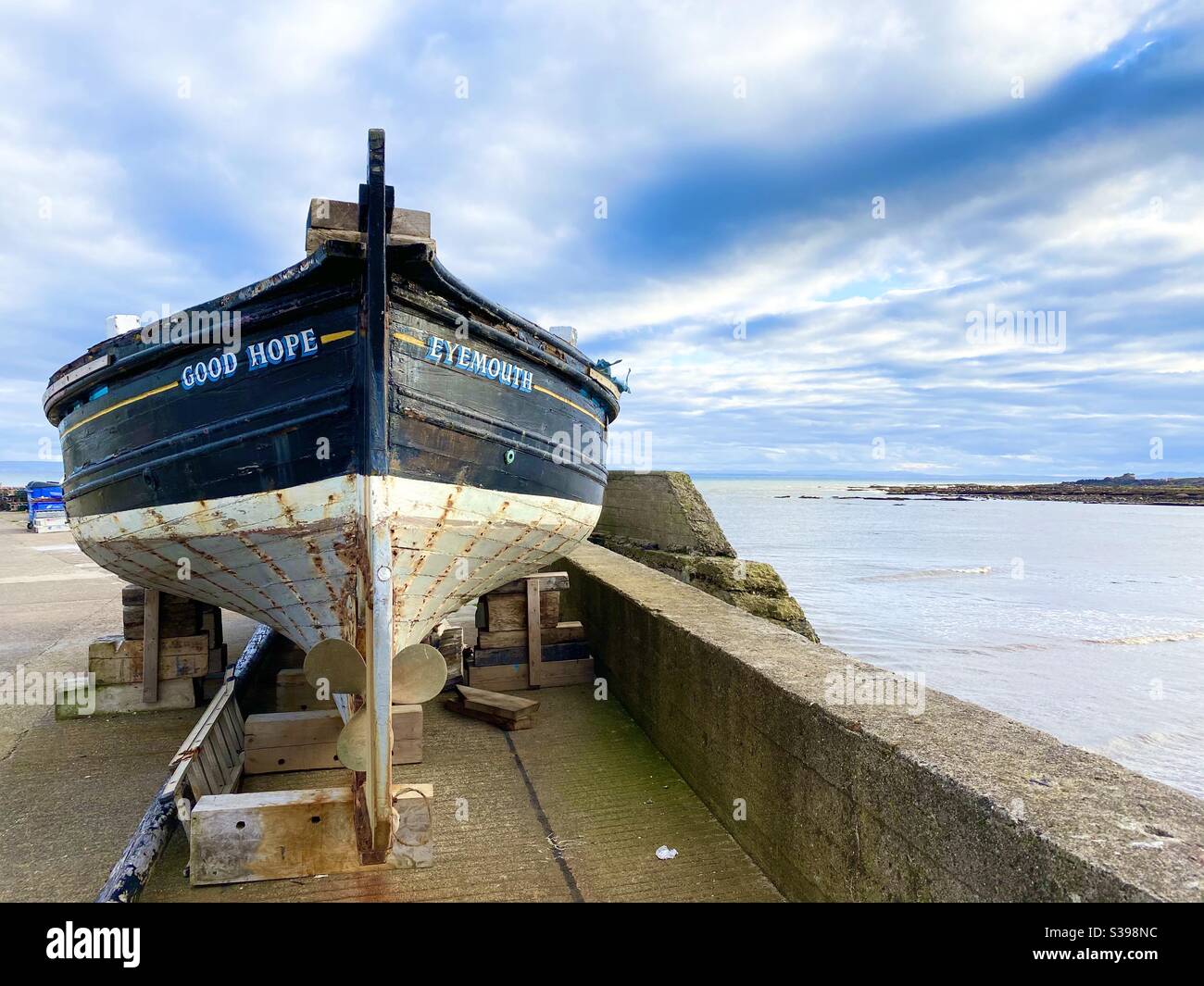Old fishing boat sat on a Scottish harbour wall Stock Photo