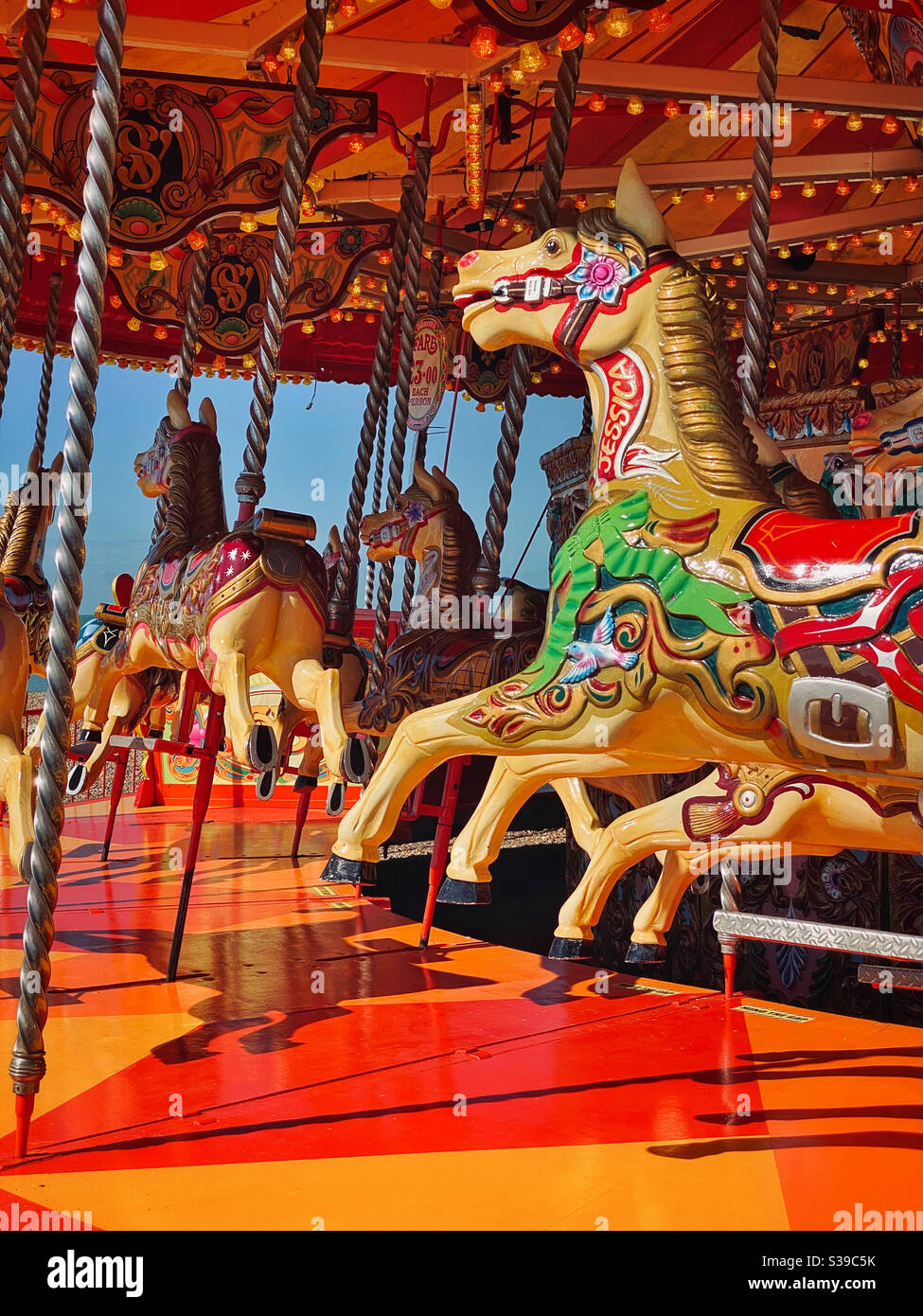 Horses on a Merry Go Round wait for child jockeys to ride them on a hot summer’s day. You can’t beat the excitement of a funfair at the seaside! Photo Credit - ©️ COLIN HOSKINS. - Smartphone Captured Stock Image
