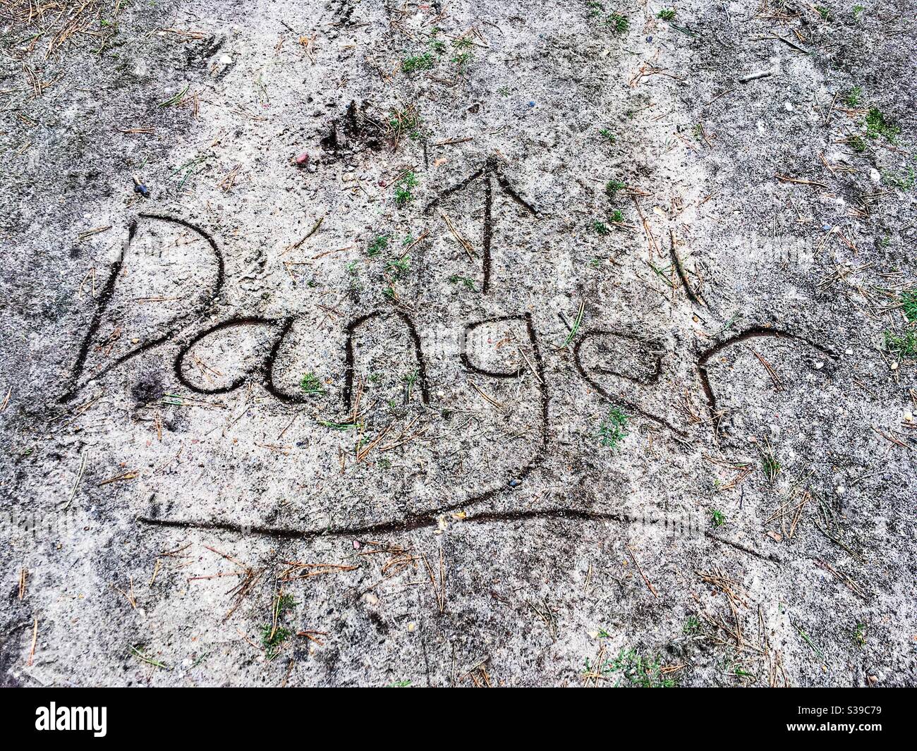 The word DANGER written on a public footpath - Smartphone Captured Stock Image