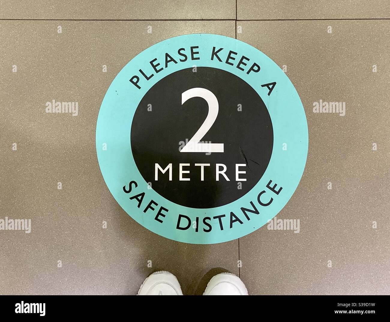 Sticker on floor of a store reminding customers of the need for social distancing - Smartphone Captured Stock Image