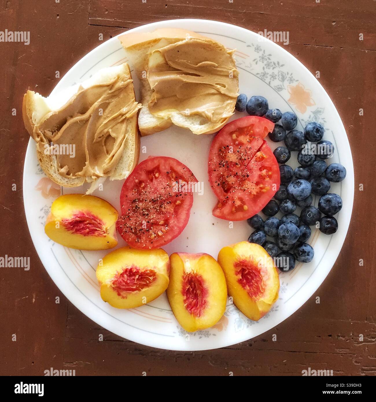 A colourful lunch with peaches, tomatoes, blueberries and bread and peanut butter. - Smartphone Captured Stock Image
