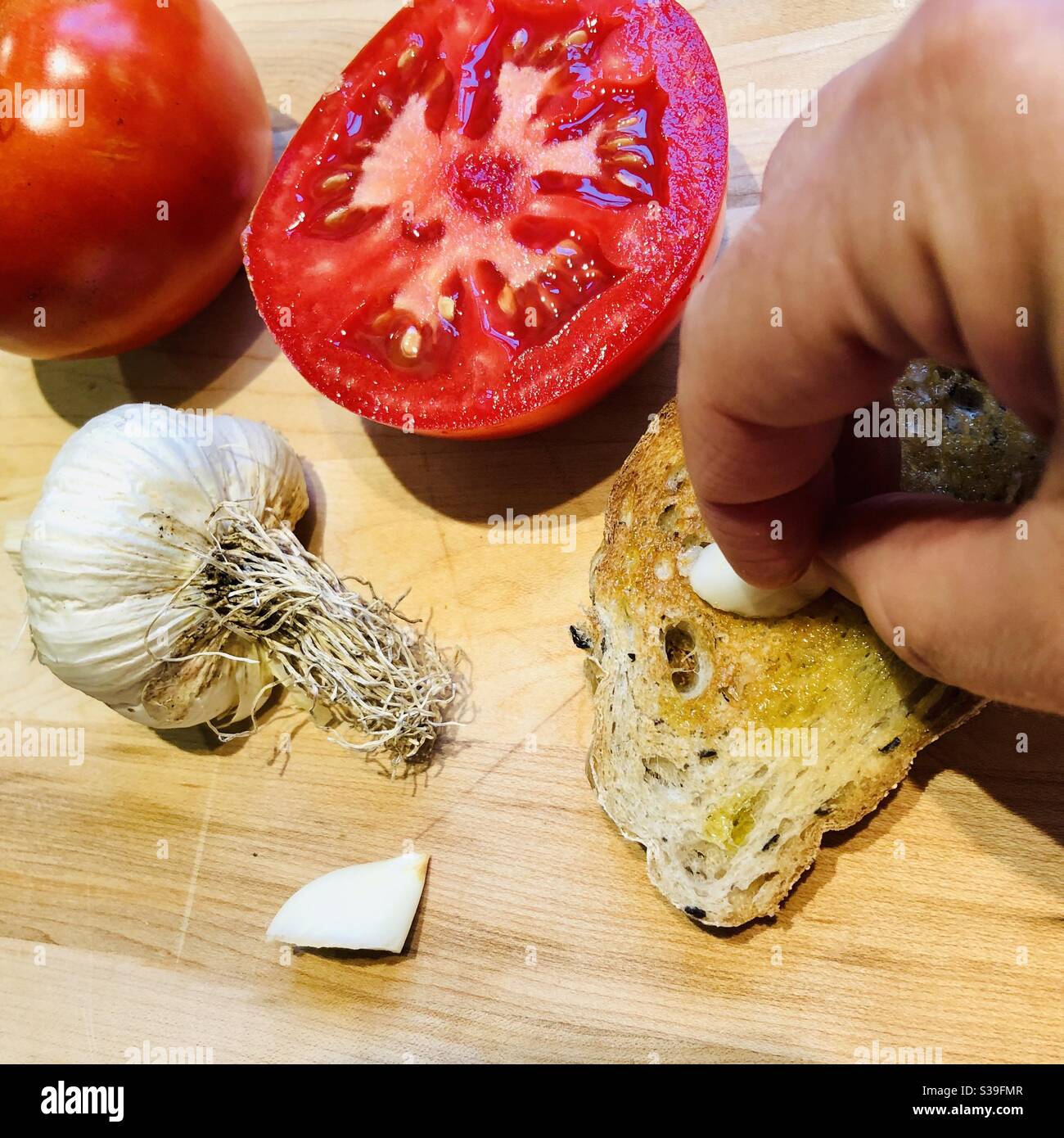 Preparation of tapas - spanish receipe of Pan tomaca - bread, garlic, tomato on a wood background - Smartphone Captured Stock Image