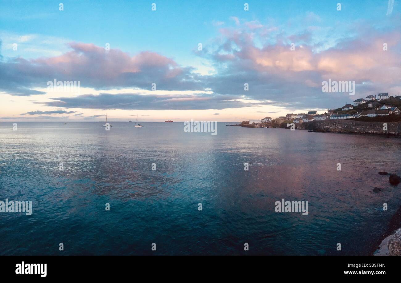Cornish seascape at sunset with colourful sky reflected in calm ocean water - Smartphone Captured Stock Image