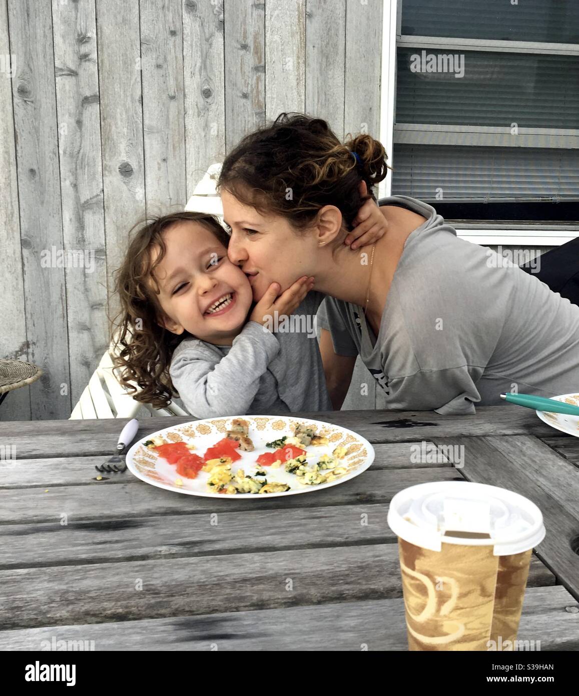 Three year old and her mom during a tender moment at an outdoor restaurant. - Smartphone Captured Stock Image