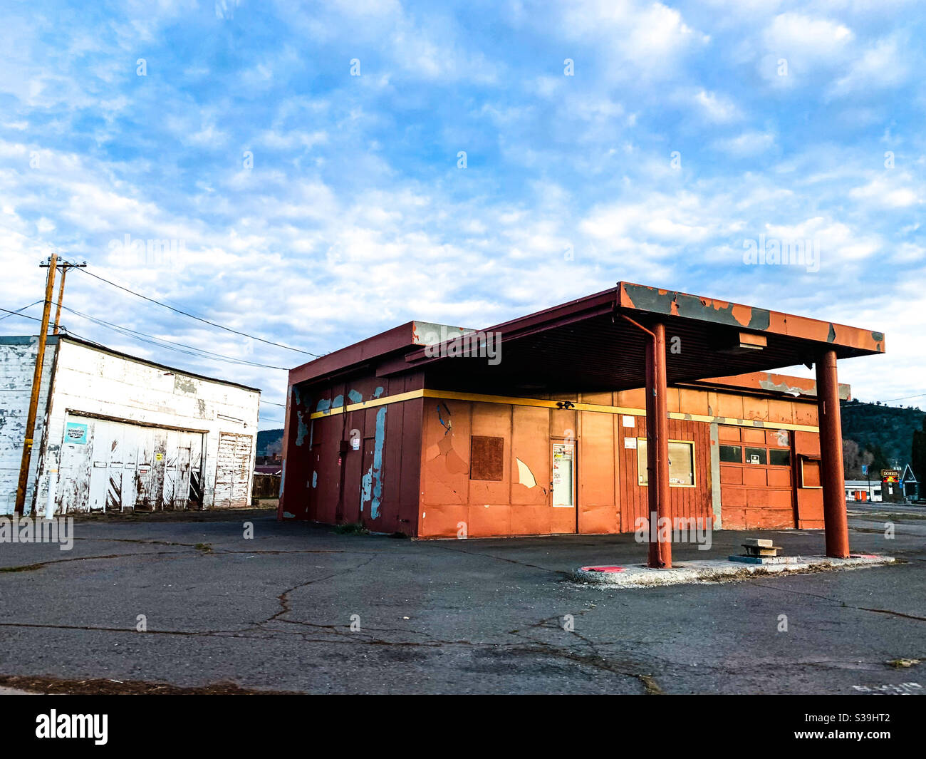 Abandoned gas station and garage in Northern California in the early morning light under blue sky and white clouds. - Smartphone Captured Stock Image