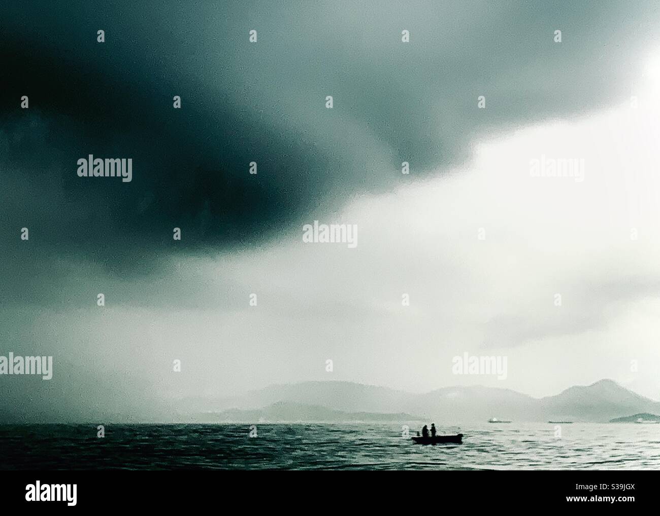 A menacing cloud behind a fishing boat in Hong Kong. - Smartphone Captured Stock Image