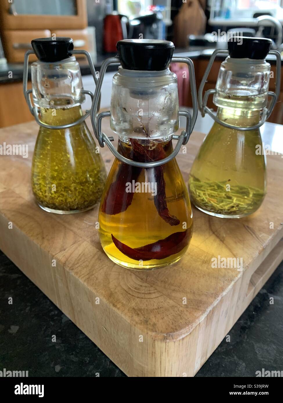 Infused olive oil in small glass bottles on a wooden chopping board in a  kitchen Stock Photo - Alamy