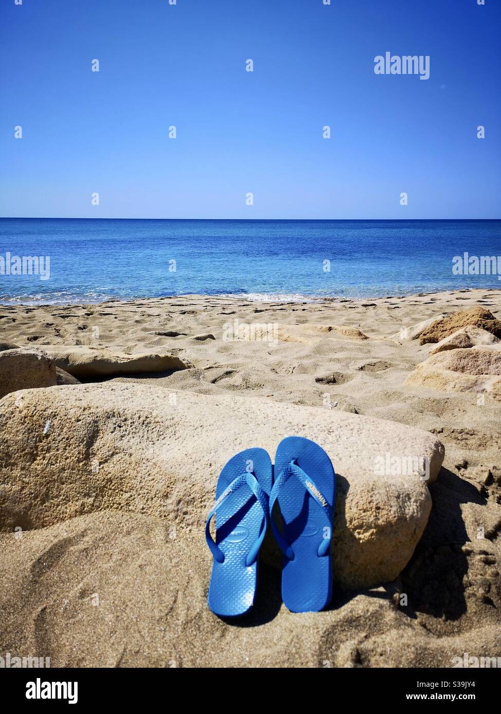 https://c8.alamy.com/comp/S39JY4/turquoise-blue-rubber-flip-flops-on-sandy-beach-S39JY4.jpg
