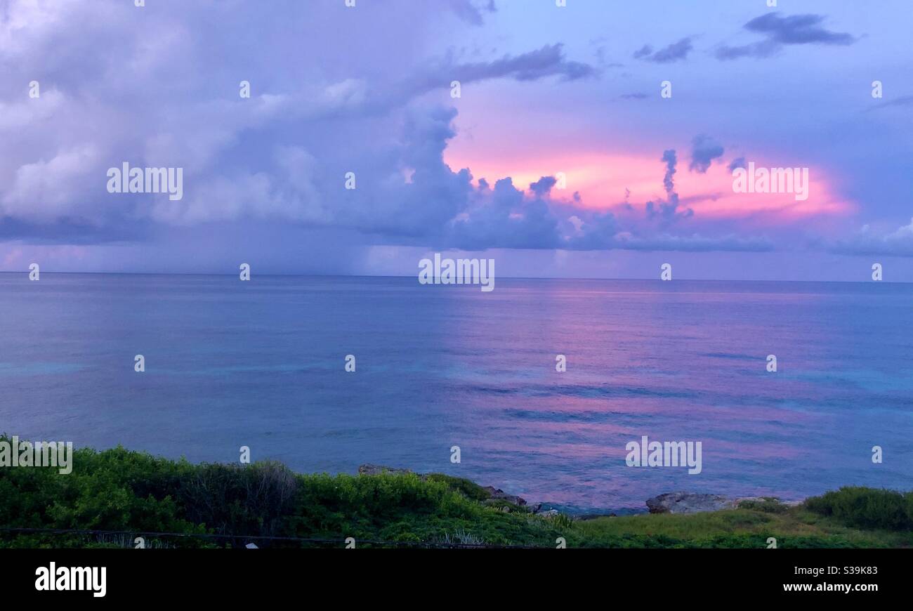 As the storm rolls in the background, the orange sky shines off the Caribbean ocean. Stock Photo