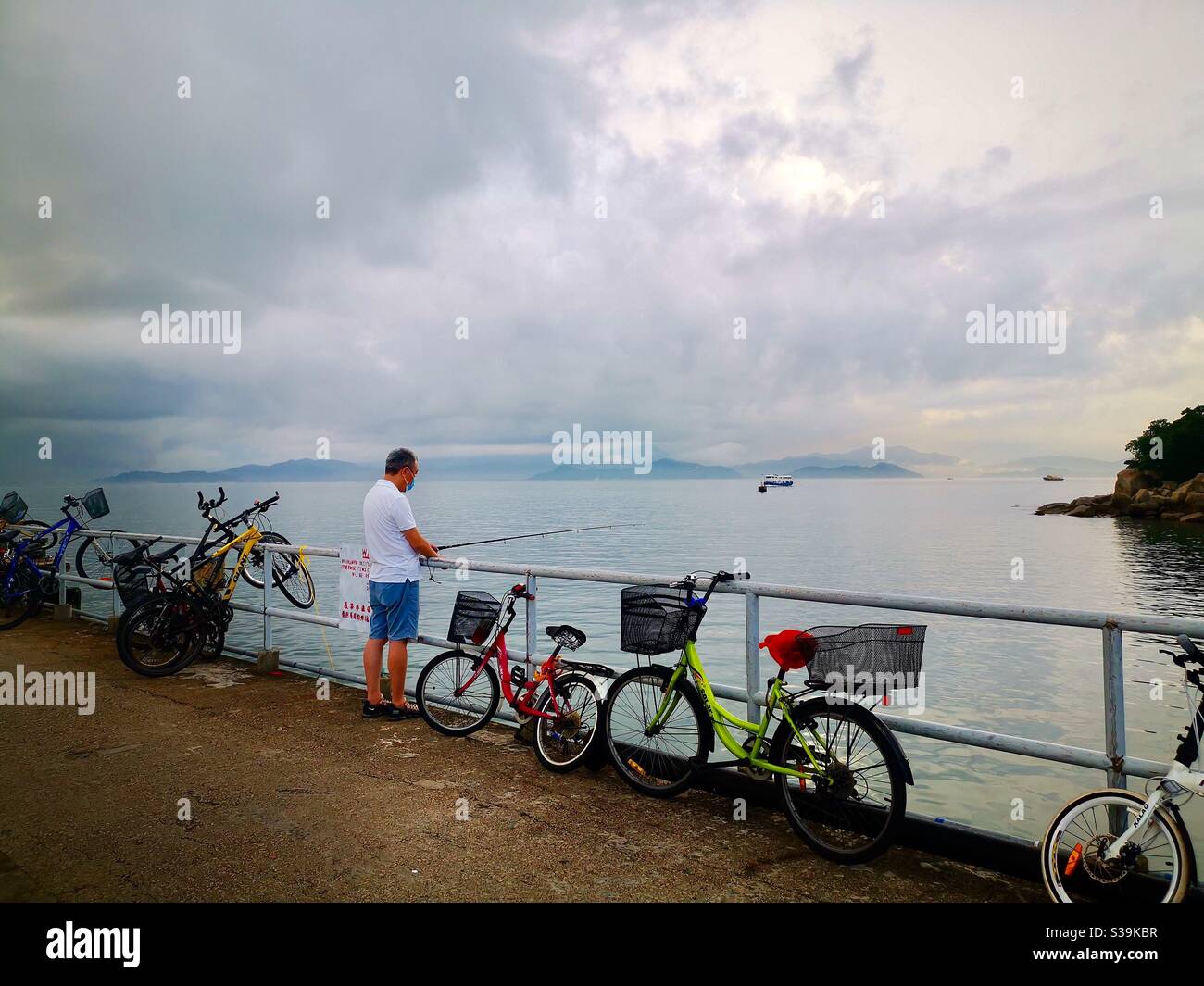 A Hong Kong Chinese man fisherman from the Yung Shue Wan pier. - Smartphone Captured Stock Image