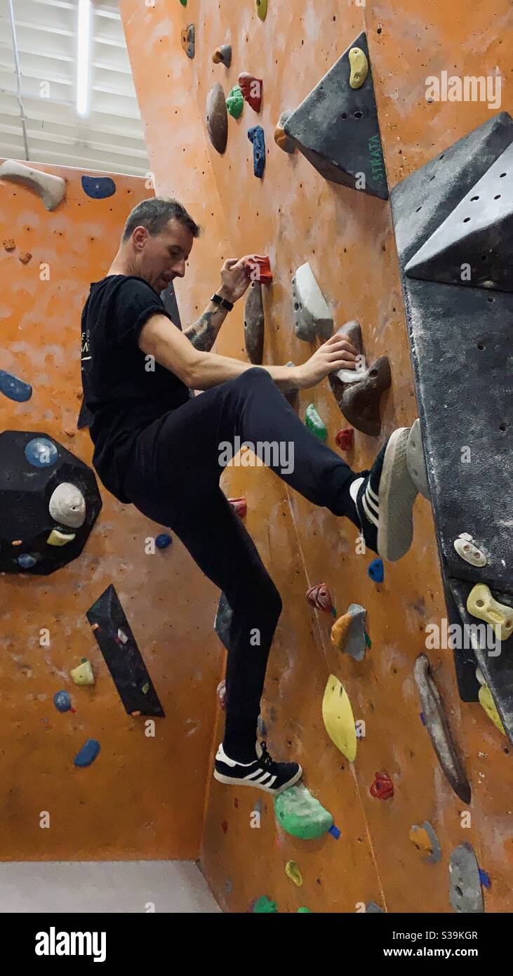 Man bouldering at indoor rock climbing centre. Stock Photo