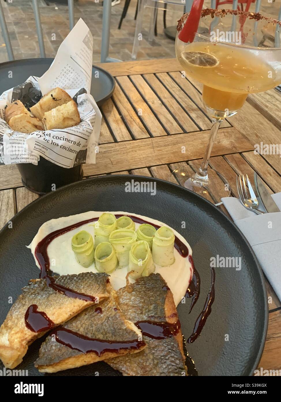 Pan friend sea bass and a spicy chilli margarita cocktail on a wooden table Stock Photo