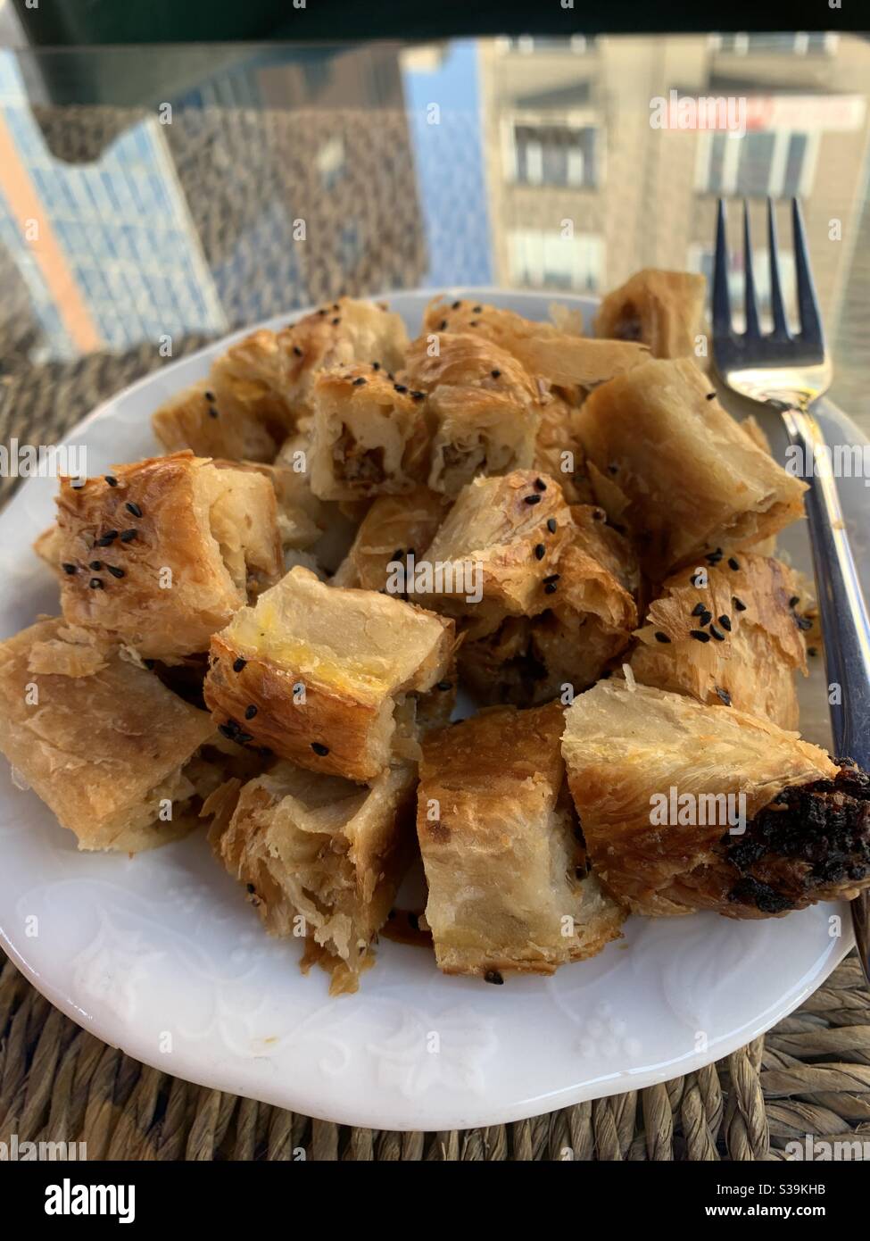 Plate of chopped meat borek on a glass reflection table - Smartphone Captured Stock Image